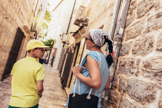 Middle-aged woman with scarf on head and her son walking through an old town