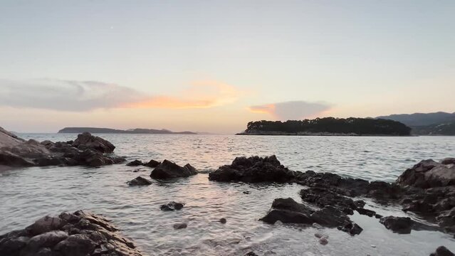 Sunset over the rocky shore at Babin Kuk Beach with Otocic Daksa in the distance in Dubrovnik, Croatia