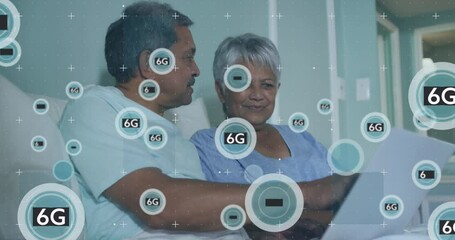 Animation of 6g over biracial senior couple using laptop in bed - Powered by Adobe