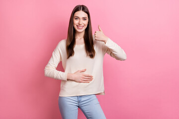 Portrait of attractive cheerful brown-haired girl touching belly showing thumbup isolated over pink...