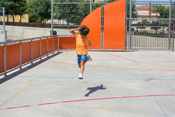 Young child of elementary age playing in the schoolyard. Toddler running and jumping on the first day of school in the school building. Image with orange colors