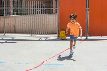 Young child of elementary age playing in the schoolyard. Toddler running and jumping on the first...