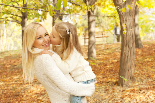 Cute happy daughter kissing her mother in cheek