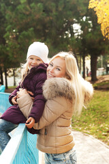 Fototapeta premium Cute happy girl hugging her mother in autumn park
