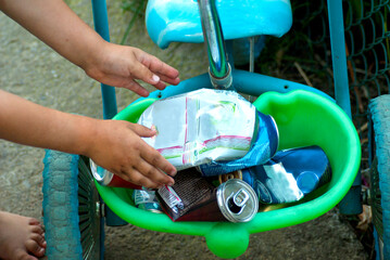 Stacking tin cans in a child's bike for further disposal by a child
