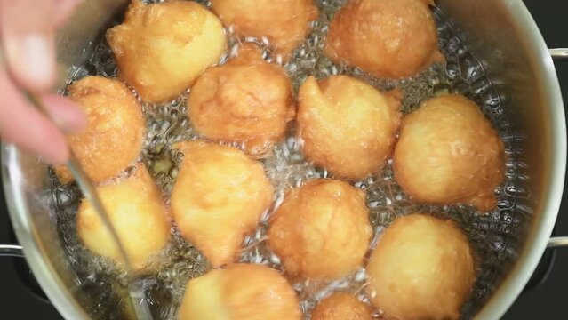 Deep frying of Portuguese donuts Sonhos.
