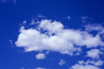Naklejka na ściany i meble A white cloud in a bright blue sky. The cloud resembles a fairy tale animal flying across the sky on a sunny day.