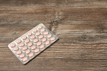 Fototapeta na wymiar full blister with pink pills on a wooden background. medicines
