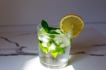 glass of cold water with fresh mint leaves and ice cubes