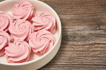 pink homemade marshmallow on a beautiful round plate on a wooden background