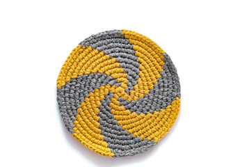 Grey yellow round spiral cup coaster on a white background. Crochet stand for hot. Kitchen tools and accessories. Modern handmade concept. Copy space. Top view. - obrazy, fototapety, plakaty