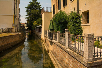 Fototapeta na wymiar The Roggia Siletto river as it flows through the historic centre of Treviso in Veneto, north east Italy. View from the Via Castelmenardo bridge 