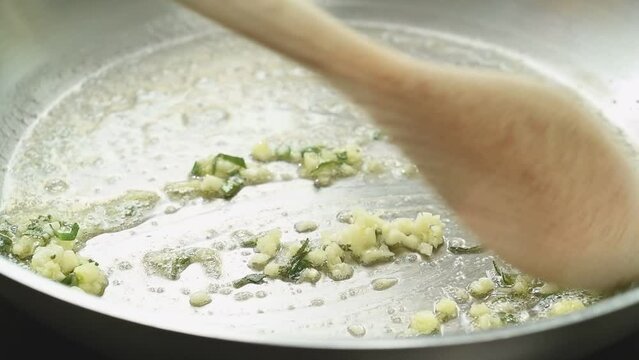 Stirring of chopped garlic and sage in a frying pan.
