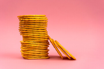 Stack of square crackers on a pink background. Dry cracker cookies as a snack for lunch. Copy space