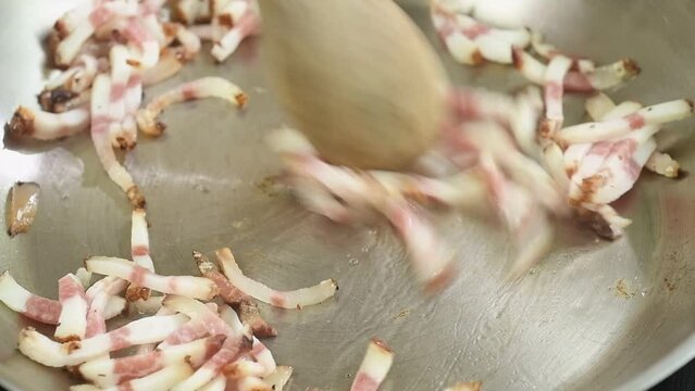 Cooking pieces guanciale in a frying pan.
