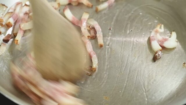 Cooking pieces guanciale in a frying pan.
