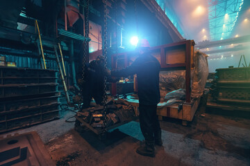 Fototapeta na wymiar Unrecognizable workers in steel mill load iron. Foundry factory, metallurgy industry.