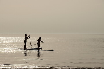 Naklejka premium Un uomo ed una donna remano vicino ad una spiaggia durante il tramonto