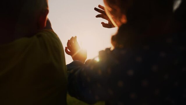 happy family kids people group pull hands to the sun teamwork. silhouette people party dancing recreation holiday lifestyle. kids at a music concert pull their hands up. religion concept sunlight