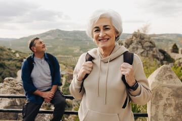 Happy senior woman hiking with her husband outdoors
