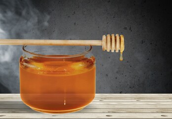 Golden honey flows from the stick and a jar.  Aromatic nectar
