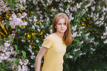teenage girl with blond hair enjoys nature. The girl is wearing a yellow summer dress.