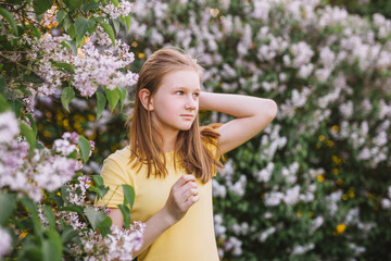 Naklejka na ściany i meble teenage girl with blond hair enjoys nature. The girl is wearing a yellow summer dress.