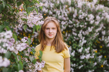 Fototapeta premium teenage girl with blond hair enjoys nature. The girl is wearing a yellow summer dress.