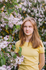 Fototapeta premium teenage girl with blond hair enjoys nature. The girl is wearing a yellow summer dress.