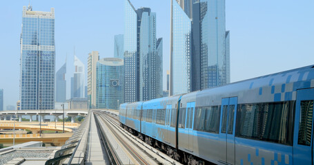 Naklejka premium Dubai, OAE, July 23, 2022 - the subway train rides on skyscrapers background