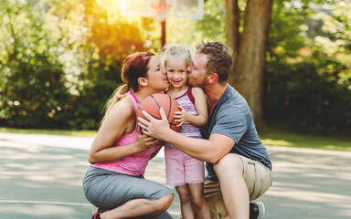 Fototapeta premium Happy family and child daughter outside at basketball court.