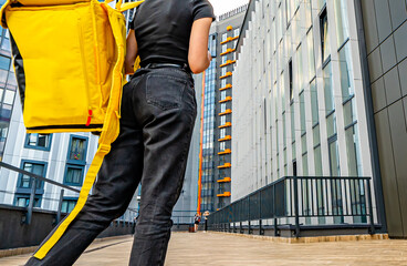 Young woman courier with food box bag working with online orders outdoors. food delivery service