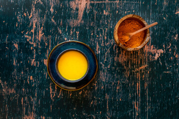 Turmeric Golden Milk on saucer and distressed green wooden surface