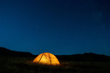 Starry sky above a tourist tent in the mountains.