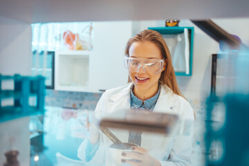 Close-up portrait of young scientist smiling. Confident female researcher is wearing protective...