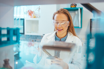 Close-up portrait of young scientist smiling. Confident female researcher is wearing protective...