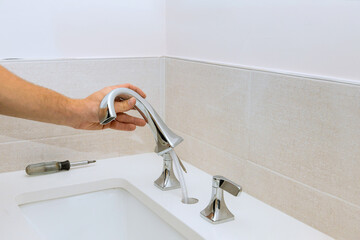 A plumber assembles a water faucet for the bathroom and installs it in the at work