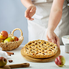 Female hands put a pear pie with  latticeon the table