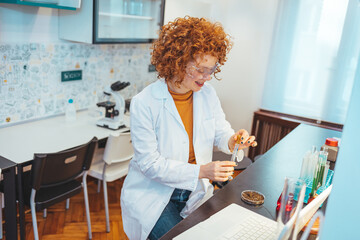 Modern laboratory interior. Woman working on medical samples in background. Young female scientist standing in her lab. Young Female Scientist Working in The Laboratory