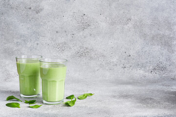 Smoothies with spinach and yogurt on a concrete stone background.