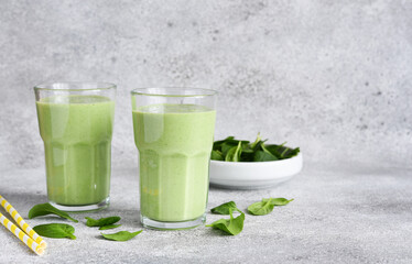 Smoothies with spinach and yogurt on a concrete stone background.