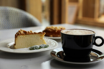 Cup of fresh coffee and desserts on table indoors