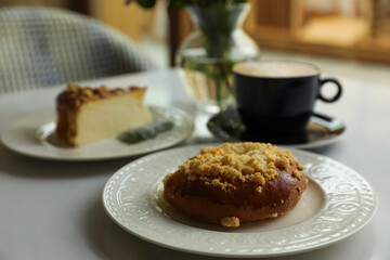 Fresh bun, tasty cheesecake and cup of coffee on table indoors
