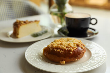 Fresh bun, tasty cheesecake and cup of coffee on table indoors