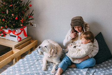 Mom and daughter comfortably cuddle at home with their pet Labrador Retriever