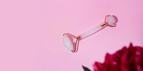 Top view of facial roller for massage on pink background.Large banner with copy space,mockup concept.