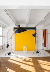 Yellow background roll with a white chair and two professional flash on a c-stands. Sunny daylight...
