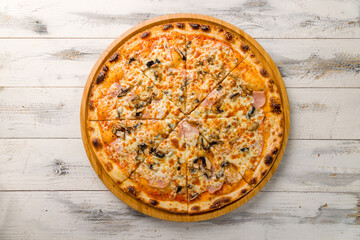 Pizza with ham and mushrooms on wooden board on white wooden table top view