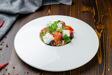Greek salad with feta on white plate on wooden table