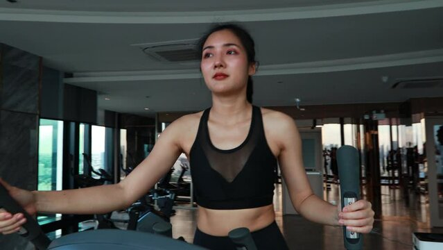 Sporty asia woman  exercising on multistation at gym for arm and shoulders muscles. Fitness exercising in gym at condo